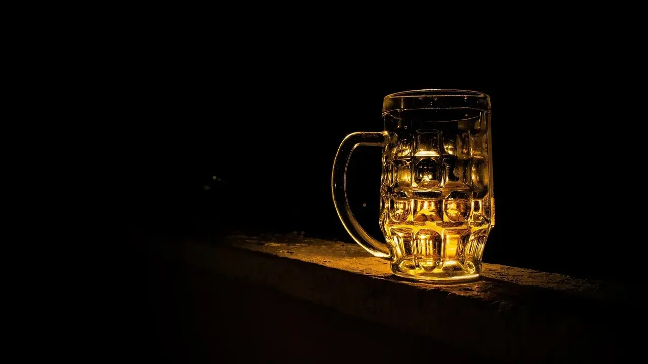 Szklanka piwa Kozel Černý, złociste światło odbija się w jej ściankach.