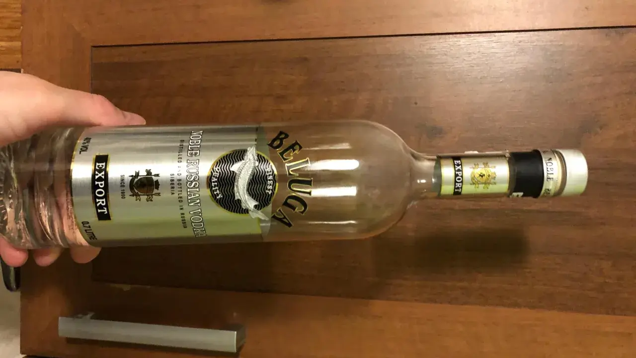 Butelka wódki Beluga Export, z etykietą "Noble Russian Vodka", leży na drewnianym blacie.