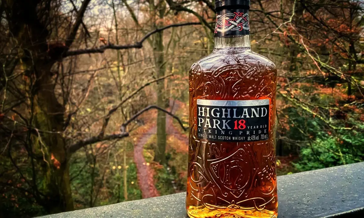 Butelka whisky Highland Park 18 Year Old na tle jesiennego lasu.