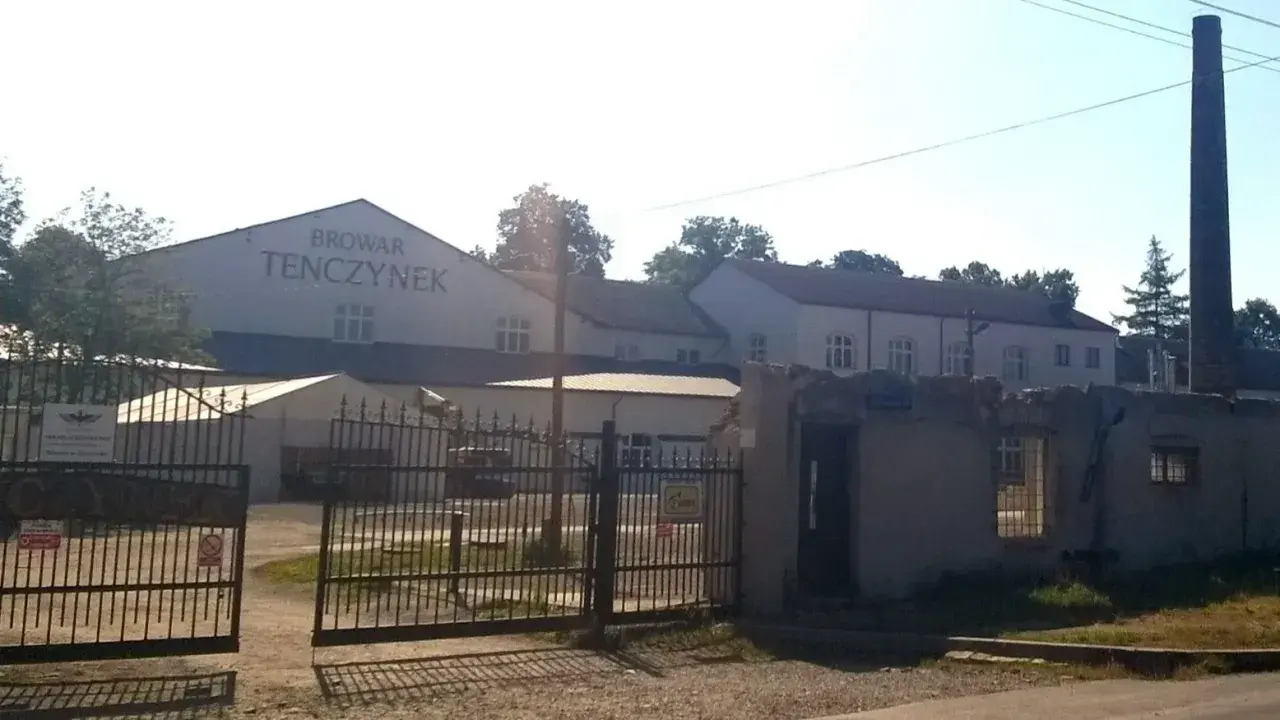 Brama wjazdowa do Browaru Tenczynek. W tle budynki browaru i wysoki komin.