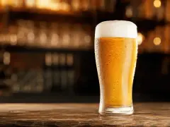 Schłodzony pilsner z obfitą pianką na blacie drewnianego baru.
