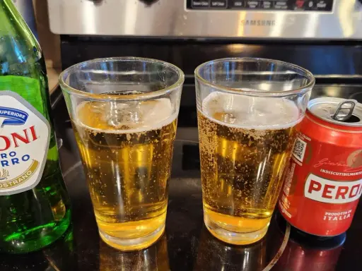 Dwa szklanki orzeźwiającego peroni piwo, obok zielona butelka i czerwona puszka. Idealne na włoskie popołudnie.