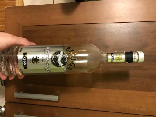 Butelka wódki Beluga Export, z etykietą "Noble Russian Vodka", leży na drewnianym blacie.