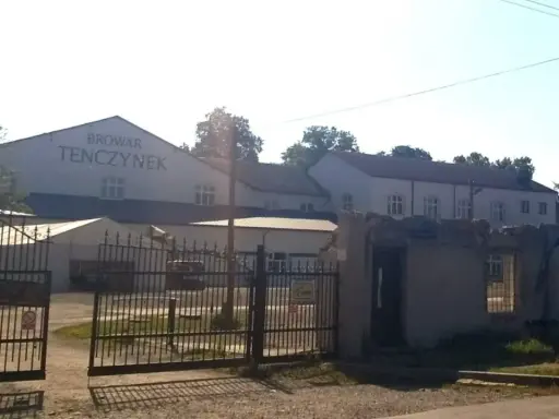 Brama wjazdowa do Browaru Tenczynek. W tle budynki browaru i wysoki komin.