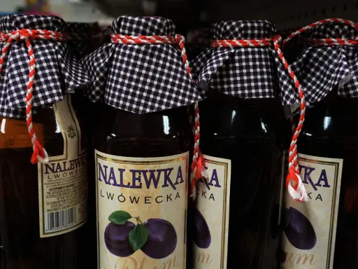 Butelki nalewki lwóweckiej z etykietami i ozdobnymi sznurkami.