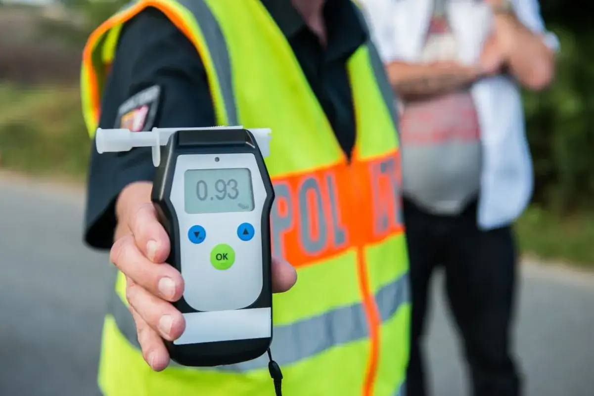 Policjant pokazuje alkomat z wynikiem 0.93 promila. To pokazuje, ile można mieć promili, by nie przekroczyć prawa.